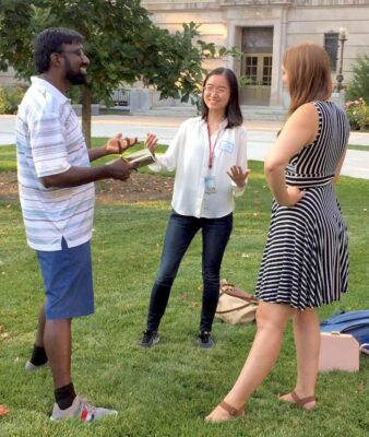 Alumni Dhyan, Lucy, and Lauren outside on the Ag Quad practicing elevator pitches
